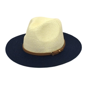 Detail of two-tone straw hat featuring white crown, navy brim, and brown leather belt trim