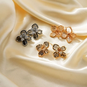 Vue détaillée des boucles d'oreilles fleur avec zircons et bordure perlée sur soie satin