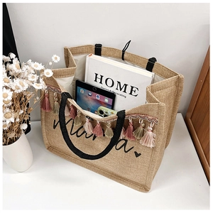Close-up of linen tote bag with colorful tassels, Mama embroidery and tablet inside