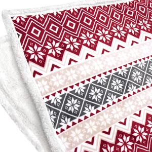 Close-up of flannel Sherpa blanket with festive red and white snowflake patterns