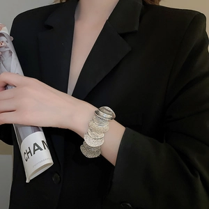 Close-up of silver textured layered scale bracelet on a wrist with business suit