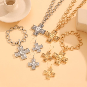 Detailed close-up of textured cross jewelry set in gold and silver finish with spiral patterns
