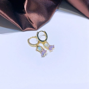 Detailaufnahme eines goldenen Ohrrings mit Bären-Anhänger und violetten Schmucksteinen