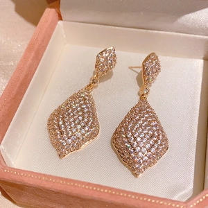 Détail de boucles d'oreilles goutte en or rose serties de zircons dans un écrin en velours