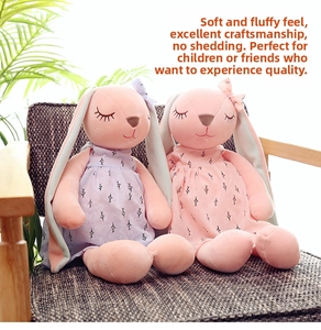 Detailed view of pink and purple bunny plush toys in dresses on a wooden chair