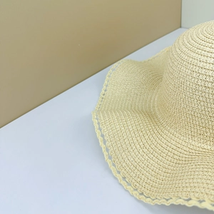 Detailed close-up of woven straw sun hat brim with delicate wave scalloped edge