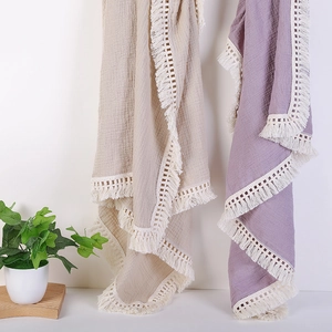 Detail of soft muslin baby blankets with white tassel lace trim in beige and purple