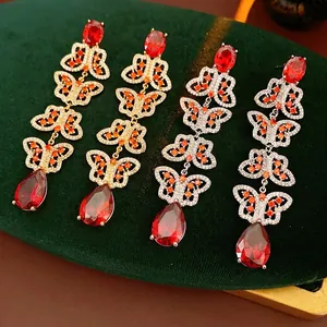 Vintage gold butterfly drop earrings with deep red gemstones and orange zircon accents