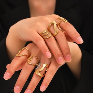 Detail shot of stackable 18K gold and silver wavy geometric rings on female model hands