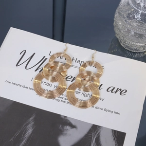 Detail of gold geometric hoop earrings with spiral metal texture on magazine background