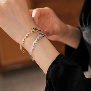 Dettaglio di bracciali a fiori oro e argento con smalto blu e zirconi a taglio baguette