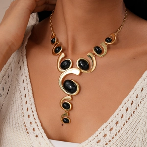 Close-up of vintage gold necklace with black oval gemstones on model neck in white top