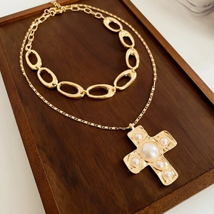 Close-up of double layer gold cross pearl necklace on a dark wooden display tray