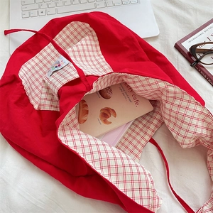 Detail of red fabric tote bag with checkered lining and interior pocket close-up