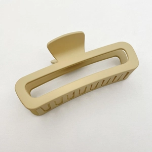 Detail of a large beige matte hair claw clip with a square design on white texture