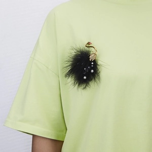 Elegante spilla a cigno con piume nere e perle su una maglietta verde acceso