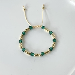 Detail of 18k gold plated beads and green crystal cube on adjustable drawstring bracelet