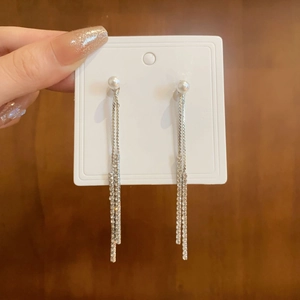 Detail of silver long tassel earrings with white pearls and double rhinestone chains