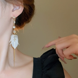 Détail de boucles d'oreilles pendantes dorées avec pétales acryliques et strass brillants