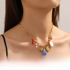 Detailed shot of bohemian gold chain necklace with red chili, pearl and shell pendants