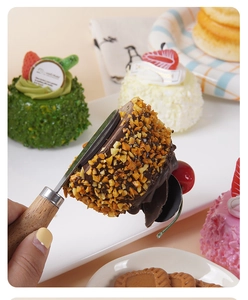 Detalle de una pala para tartas de madera y metal levantando un postre de chocolate