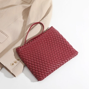 Elegant red woven leather clutch bag styled on a beige blazer for a high-fashion look