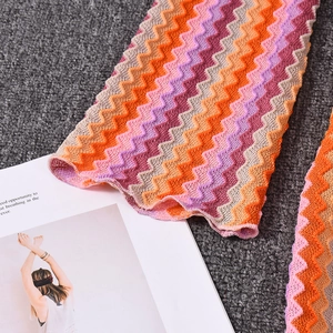 Macro detail of wave pattern knit dress featuring orange, purple, and beige textured yarns