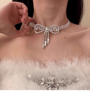 Dettaglio di un'elegante collana a fiocco con nappe di cristallo e perle sulla modella