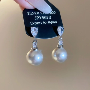 Dettaglio di orecchini in argento S925 con zircone a goccia e pendente di perla bianca