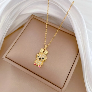 Golden bunny pendant necklace with colorful crystals on a soft white silk background