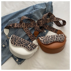 Detailed view of white and brown leopard print saddle bags with wide woven straps