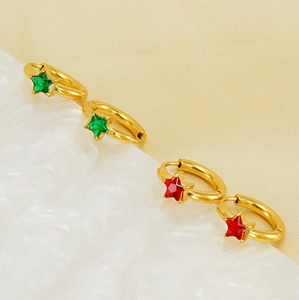 Détail de boucles d'oreilles étoiles dorées ornées de zircons rouges et verts