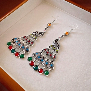 Detailed macro of vintage peacock earrings with multi-colored crystals and silver fringe
