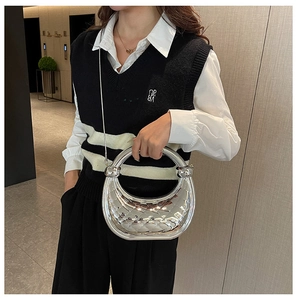 Detail of silver metallic crescent handbag with quilted diamond pattern and round handle