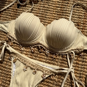 Detail of shell-shaped bikini top with starfish charms on a woven straw mat