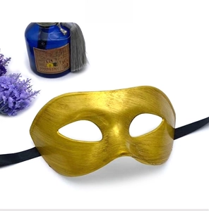 Macro shot of retro gold half-face mask featuring metallic brushed texture and black ribbons