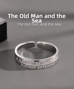 Macro shot of silver ring engraved with 'A man can be destroyed but not defeated' text