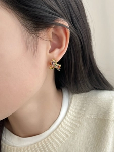 Close-up of gold plated pony earring with colorful zircons on a model side profile