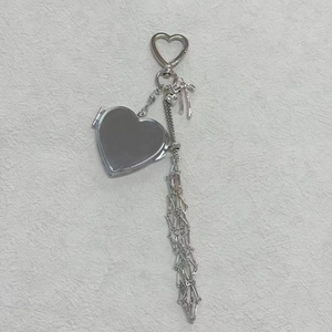 Silver heart-shaped mirror pendant with metallic tassel and bow charm details
