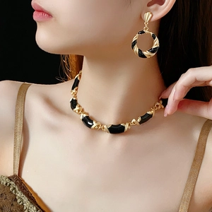 Detail view of vintage gold twisted necklace and earrings set with black enamel accents