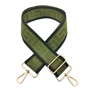 Close-up of olive green wide bag strap with Greek key pattern and gold metal hardware