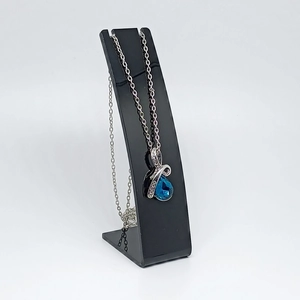 Detailed view of teardrop blue pendant necklace displayed on a black stand
