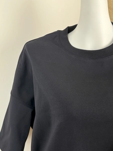 Close-up of the ribbed crew neck and premium cotton knit texture on a black sweatshirt