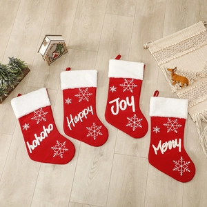 Set of 4 red knitted Christmas stockings with white snowflake embroidery on wood floor