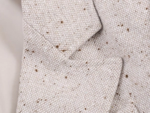Gros plan du col d'un blazer en tweed montrant la texture de la laine et le fini moucheté