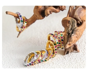 Detail of gold and silver eternity rings with colorful cubic zirconia on a wooden display