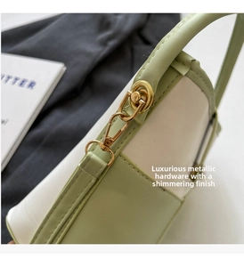Dettaglio fibbie metalliche dorate su borsa a secchiello a contrasto verde e bianco