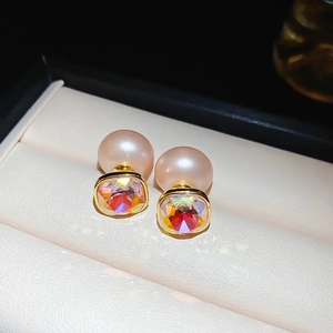 Vue macro de boucles d'oreilles en perle rose et cristal dans un coffret de luxe