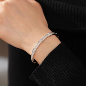 Macro shot of silver X-shaped bangle with micro-paved cubic zirconia on a model