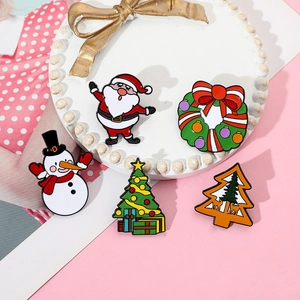 Close-up of five colorful Christmas enamel pins on a decorative white display plate